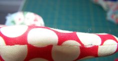 a close up of a red and white polka dot print cloth on a sewing machine