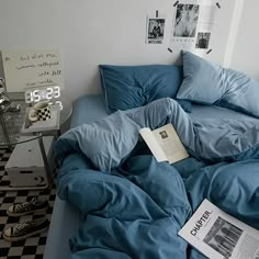 an unmade bed with blue comforter and pillows on it, next to a checkered floor