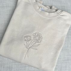 "A grouping of 2 peonies (November's birth month flower) embroidered on a cozy crewneck sweatshirt in your choice of thread color. Design is hand drawn and digitized by me, then stitched in house by embroidery machine. A great gift for a November birthday, a mom of 1 born in November, a mom of November twins, as a commemoration of a loved one, or just for someone who loves peonies! Further customize by going to my shop section \"sweatshirt add-ons\" and adding something special to the sleeve, su Embroidered Floral Sweatshirt, Birth Flower Sweatshirt, Cute Embroidered Crewneck, Embroidery Tshirt Designs, Embroidery Designs Crewneck, Machine Embroidered Sweatshirt, Machine Embroidered Sweatshirt Ideas, Embroidery Designs On Sweatshirts, Crewneck Embroidery Ideas