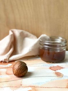 a jar of peanut butter sitting on top of a wooden table next to a walnut