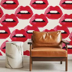 a leather chair sitting in front of a wall with red lips on it