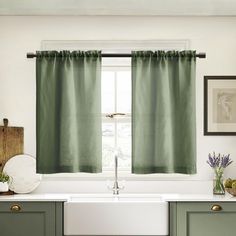 a kitchen with green curtains and white sink