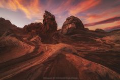 some very pretty rocks in the middle of a big desert area with sunset behind them