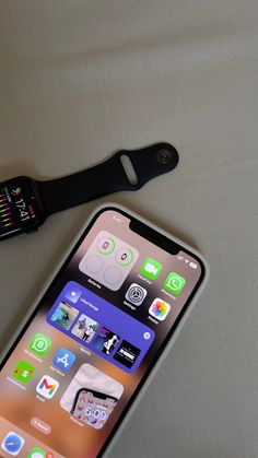 an apple watch sitting on top of a bed next to an iphone with the app icons displayed