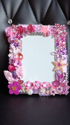 a pink and purple frame with flowers on the bottom is sitting on a black leather chair