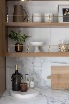 a kitchen with marble counter tops and wooden shelves