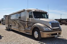 an rv parked on gravel with other vehicles in the background