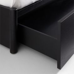 a close up of a bed with a black headboard and night stand next to it