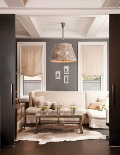 a living room filled with furniture and a light fixture hanging over the top of it