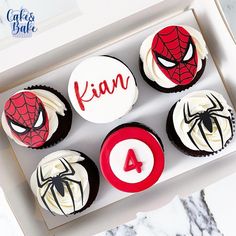 four decorated cupcakes in a box with spiderman and captain america on them