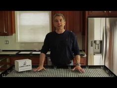 a man standing in front of a kitchen counter with an oven and refrigerator behind him