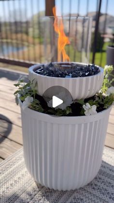 a large white planter sitting on top of a wooden deck next to a fire