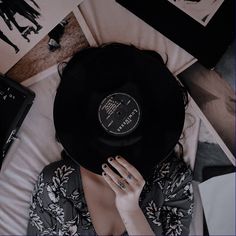 a woman laying on top of a bed with a record in her hand and other items around her