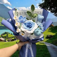 a person holding a bouquet of flowers in front of a lake and mountains with the words flower studio written on it