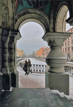 two people are standing under an archway on the sidewalk in front of some old buildings