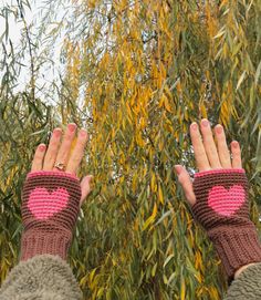 two hands with knitted wrist warmers in front of trees