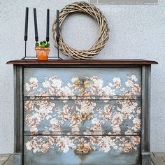 an old dresser with flowers painted on it and some candles sitting on top of it