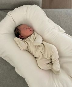 a baby is sleeping on a pillow on the couch with it's eyes closed