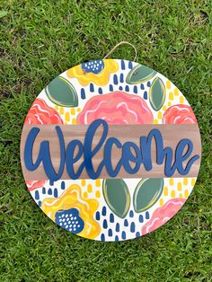 a welcome sign sitting on top of green grass