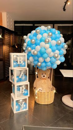 a teddy bear is sitting in a basket with balloons on it and the words baby spelled out