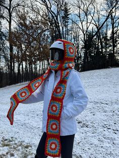 a person wearing a helmet and scarf standing in the snow