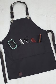 a black apron with scissors, combs and other items in it on a white surface