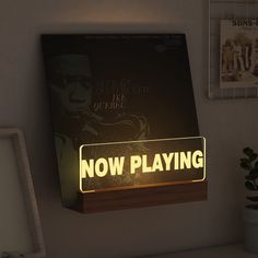 there is a sign that says now playing on the wall next to a potted plant