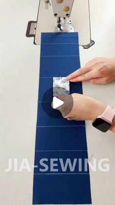 a woman is using a sewing machine to sew on a piece of blue fabric