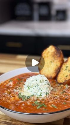 a bowl of tomato soup with garlic bread on the side and an appetizer in the background