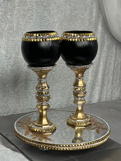 two black goblets sitting on a gold plate