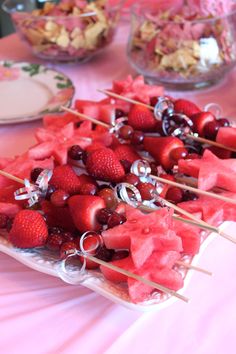 watermelon and strawberries on skewers with other food items in the background