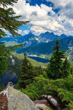 the mountains are covered with trees and water in the distance is a lake surrounded by rocks