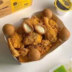 a box filled with fried food sitting on top of a white table next to a carton of mayonnaise