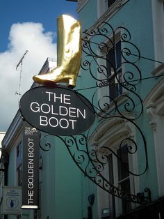 the golden boot sign is hanging from the side of a building with a gold shoe on it