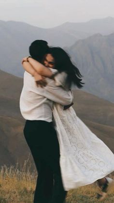 two people hugging each other on top of a hill