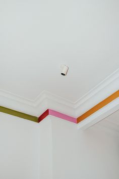 an empty room with white walls and multicolored stripes painted on the ceiling above