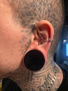 a man with tattoos and piercings on his ear is wearing a chain around his neck