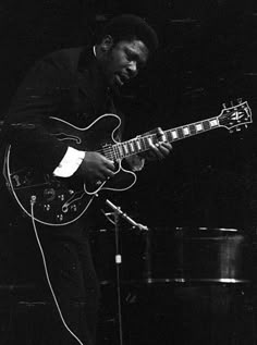 a black and white photo of a man playing an electric guitar