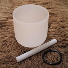 a white cup sitting on top of a fur covered floor next to a pair of scissors