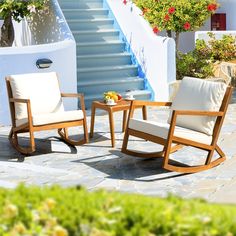 two wooden rocking chairs sitting next to each other on a stone patio with stairs in the background