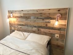 a bed with two lights on each side of it and a headboard made out of wooden planks