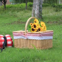 a picnic basket with sunflowers in the grass