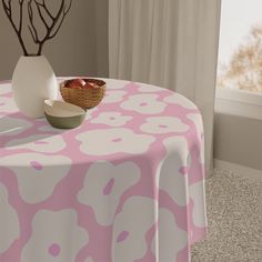 a pink and white table cloth with flowers on it next to a bowl of fruit