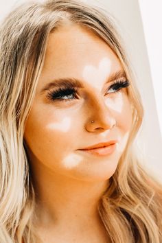 a woman with long blonde hair and blue eyes is looking at the camera while wearing an orange top