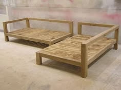 two wooden benches sitting next to each other on the ground in front of a wall