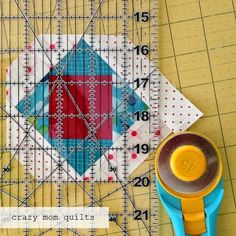 a ruler and some scissors sitting on top of a piece of paper next to a quilt