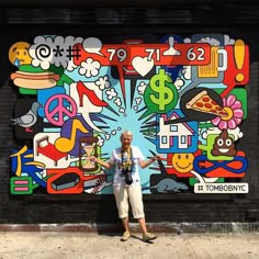 a man standing in front of a mural on the side of a building