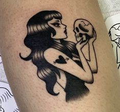 a woman with a skull tattoo on her leg is holding a human skull in her right hand