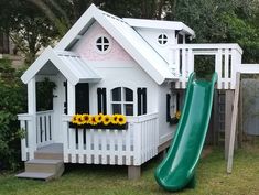 a white house with a green slide in the yard