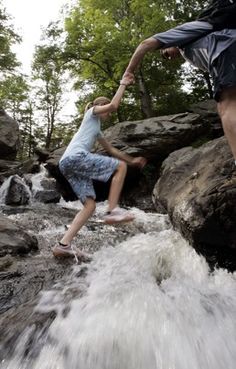 two people jumping off rocks into a river